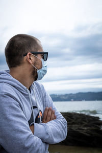 Man holding sunglasses against sea against sky