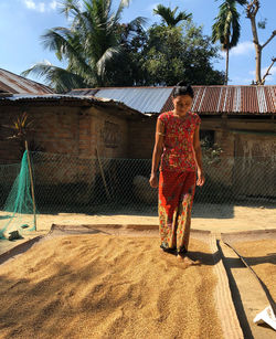 Full length of young woman drying rice by foot.