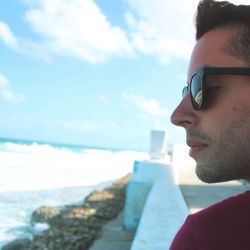 Side view of man at beach against sky