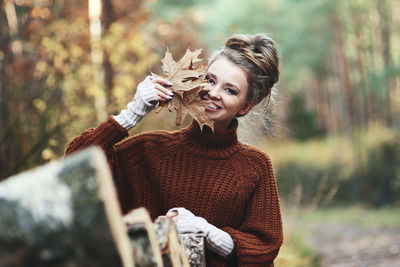 Portrait of smiling young woman holding plant