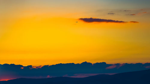 Scenic view of dramatic sky over silhouette landscape