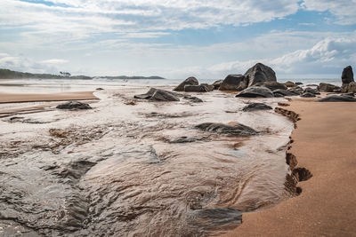 Rocks on beach against sky