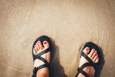 Low section of woman standing on sand