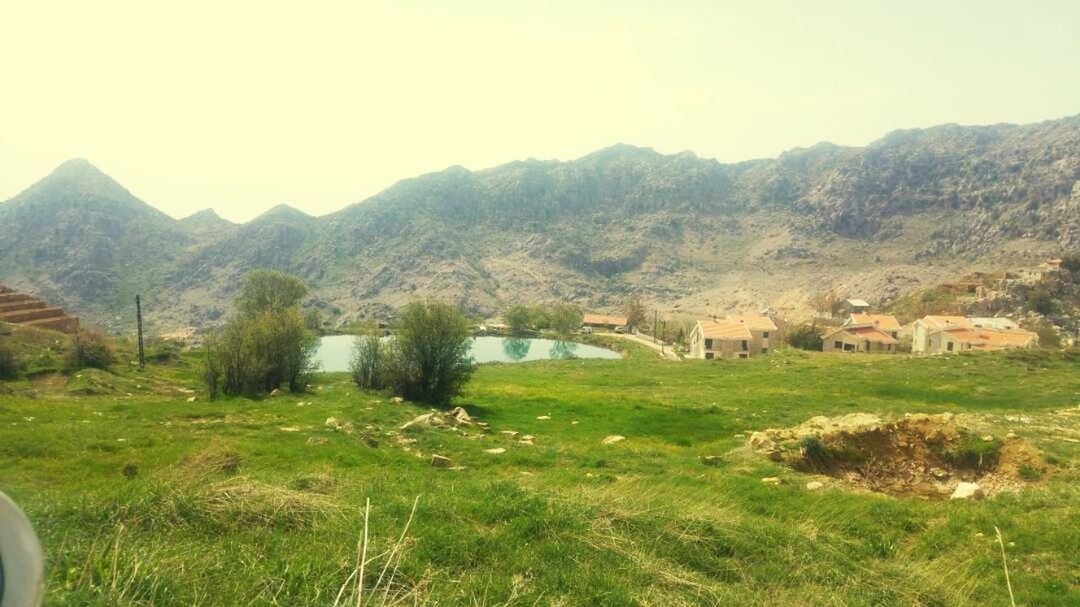 mountain, landscape, grass, tranquil scene, field, tranquility, nature, no people, scenics, outdoors, mountain range, day, beauty in nature, architecture, agriculture, tree, built structure, growth, building exterior, rural scene, clear sky, sky