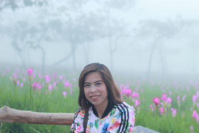 Portrait of smiling woman in forest during foggy weather