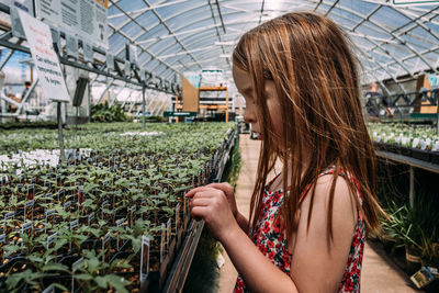 Close up of young girl at a green house looking at plants