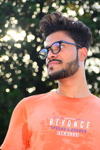 Portrait of young man standing against tree