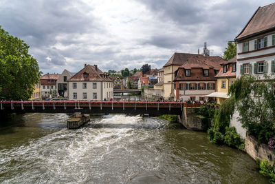 Buildings by river against sky