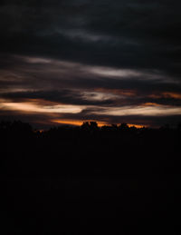 Silhouette landscape against dramatic sky during sunset