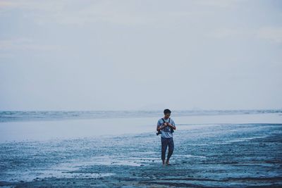 Full length of man walking on shore at beach against sky