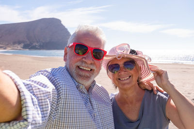Portrait of smiling man with woman at beach against sky