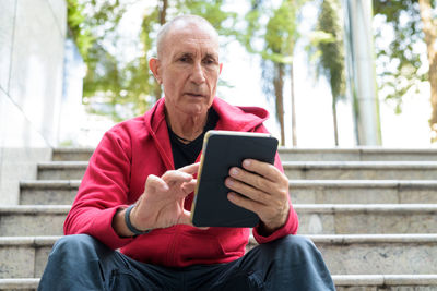 Mid adult man using mobile phone while sitting outdoors