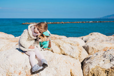 Rear view of woman sitting on rock at beach