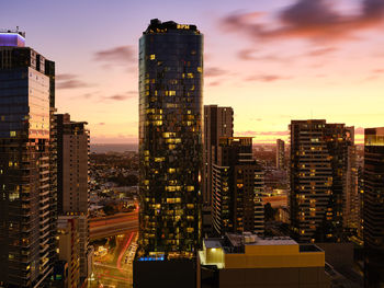 Modern buildings in city against sky during sunset