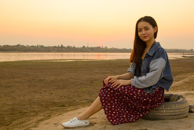 Portrait of smiling young woman sitting on land