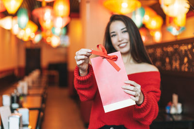 Midsection of woman holding camera while standing at home