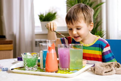 Playful boy mixing color in water at home