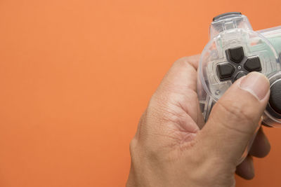 Close-up of man holding hands against orange background