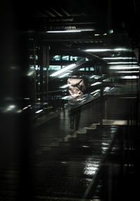 Woman standing at railroad station platform seen through train window at night