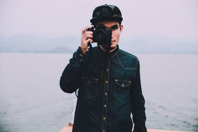 Man photographing with camera against sky