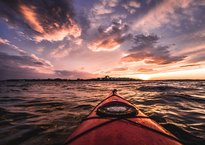 Pov from red kayak during vibrant sunset in portland harbor, maine