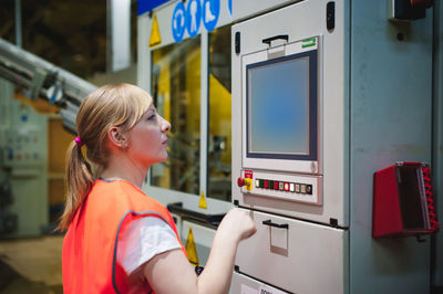 Side view of mid adult woman operating machinery