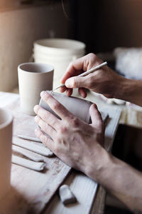 Midsection of woman working with coffee cup on table