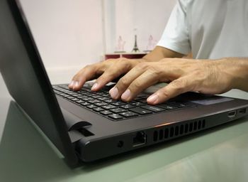 Midsection of man using laptop on table