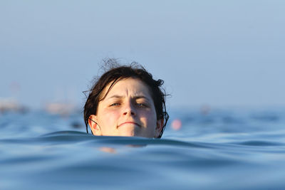 Portrait of young woman swimming in sea against clear sky