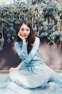 Portrait of beautiful young woman sitting against plants