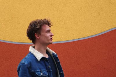 Portrait of young man looking away against wall