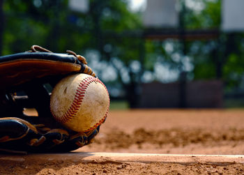Close-up of baseball in glove on field