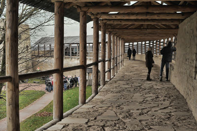 Rear view of people walking on colonnade of building