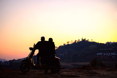 Silhouette people riding motorcycle against sky during sunset