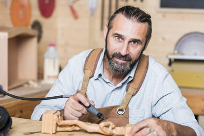 Portrait of carpenter carving on figurine in workshop