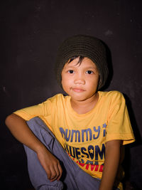 Portrait of cute boy wearing hat against black background