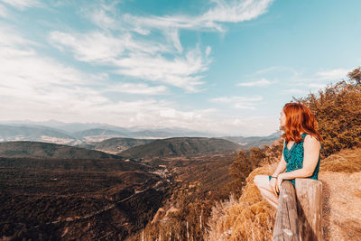 Woman looking at view of mountain range against sky