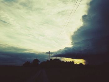Electricity pylon against cloudy sky