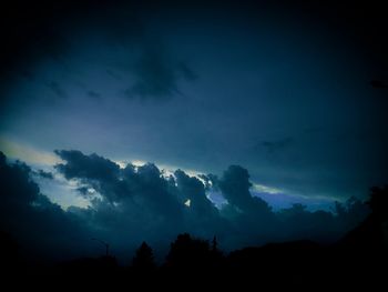 Low angle view of silhouette trees against blue sky