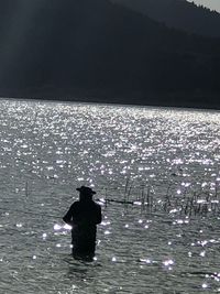 Rear view of silhouette man standing in lake against sky