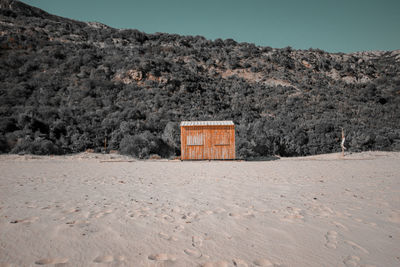 House on field by mountain against sky