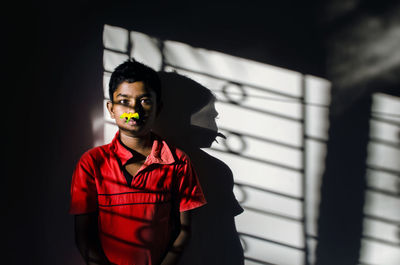 Portrait of boy with toy in nose standing against wall