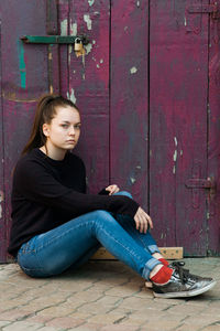 Young woman sitting on door