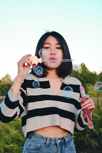Portrait of beautiful young woman holding bubbles