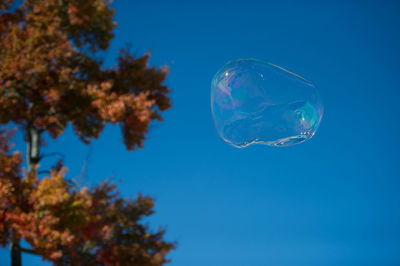 Low angle view of bubbles against clear blue sky