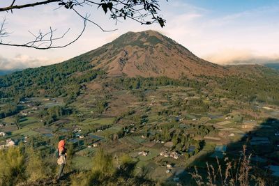 High angle view of woman looking at mountain while standing on cliff