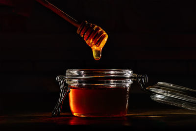 Honey with a natural wooden stick on black background