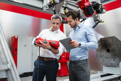 Male engineers working with robotic equipment in factory