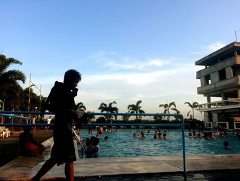 Man standing at swimming pool against sky