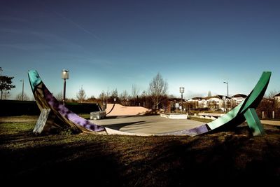 Boats moored on field against clear blue sky